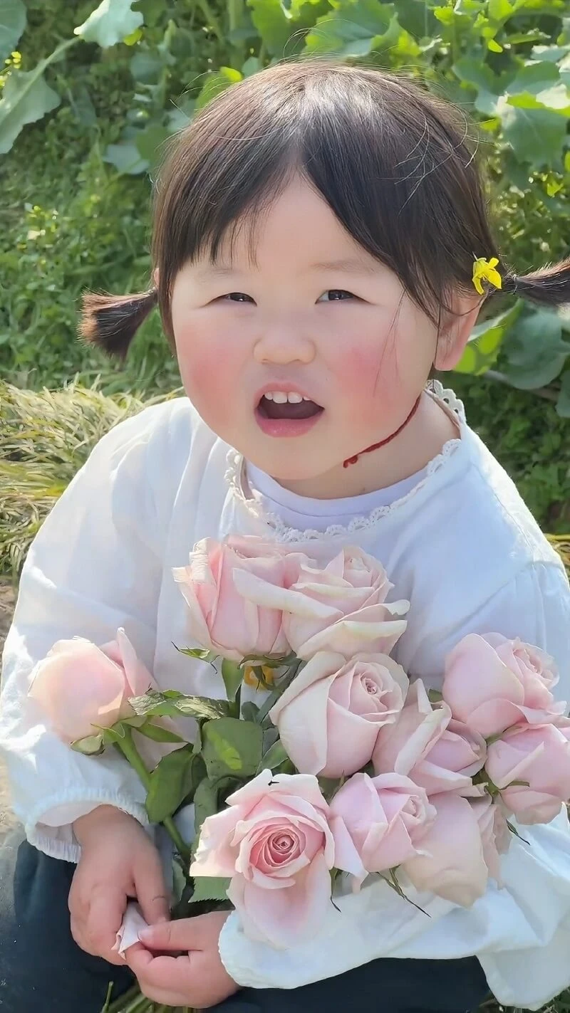 Một cô bé đang cầm một bó hoa hồng hình nền em bé cute