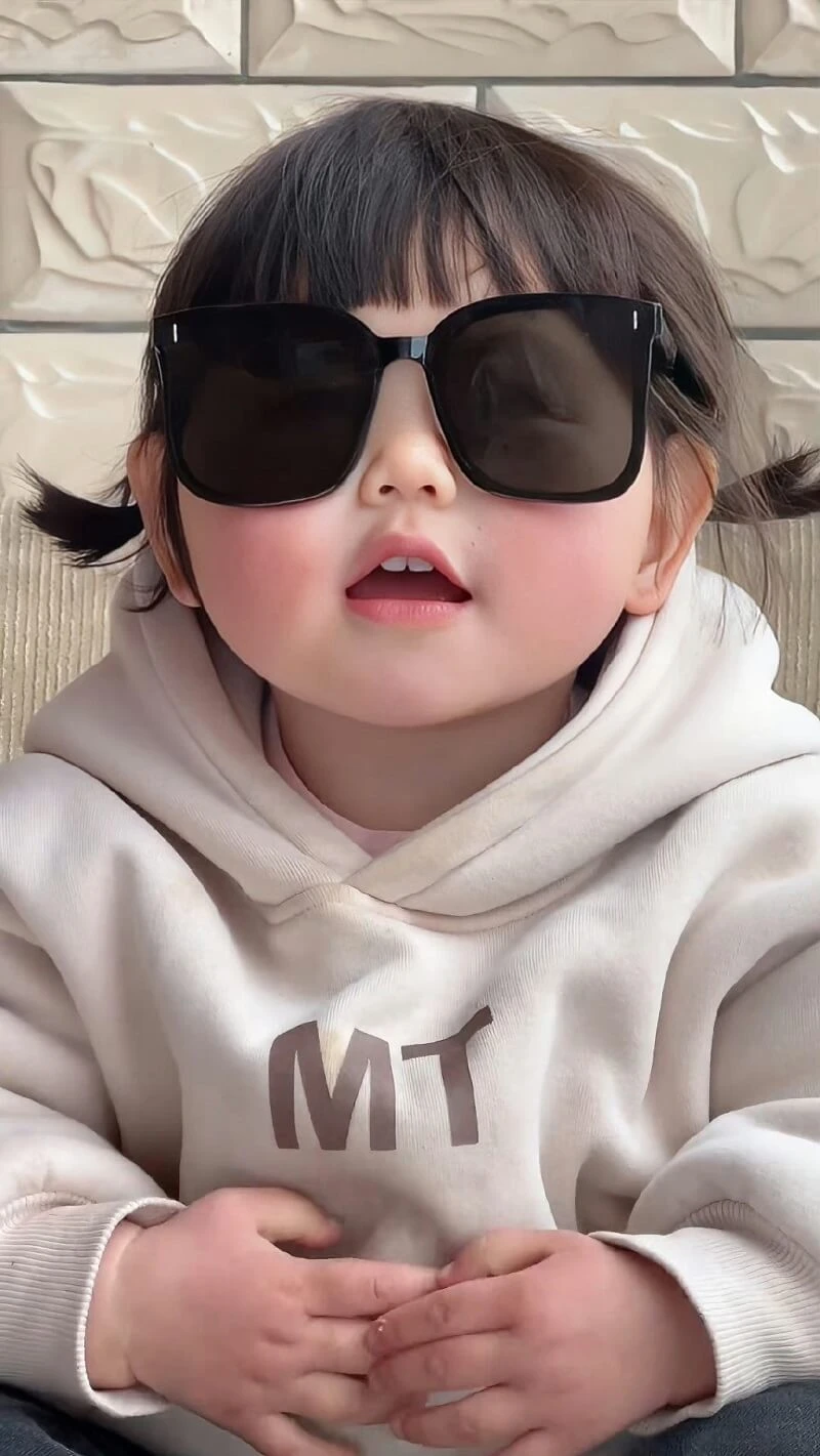 Một cô bé đeo kính râm và áo hoodie trắng hình nền em bé dễ thương