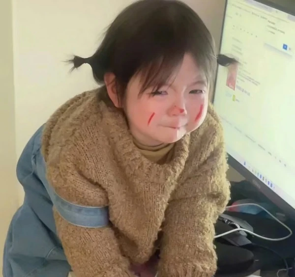 Một cô bé đang ngồi trên sàn và nhìn vào máy tính meme buồn