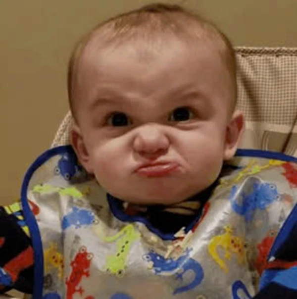 Một em bé ngồi trên ghế cao với PAC meme tức giận