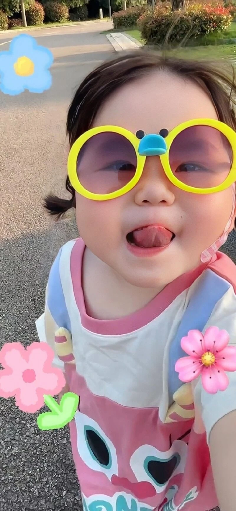 Một cô bé đeo kính râm và cầm một bông hoa ảnh nền em bé dễ thương