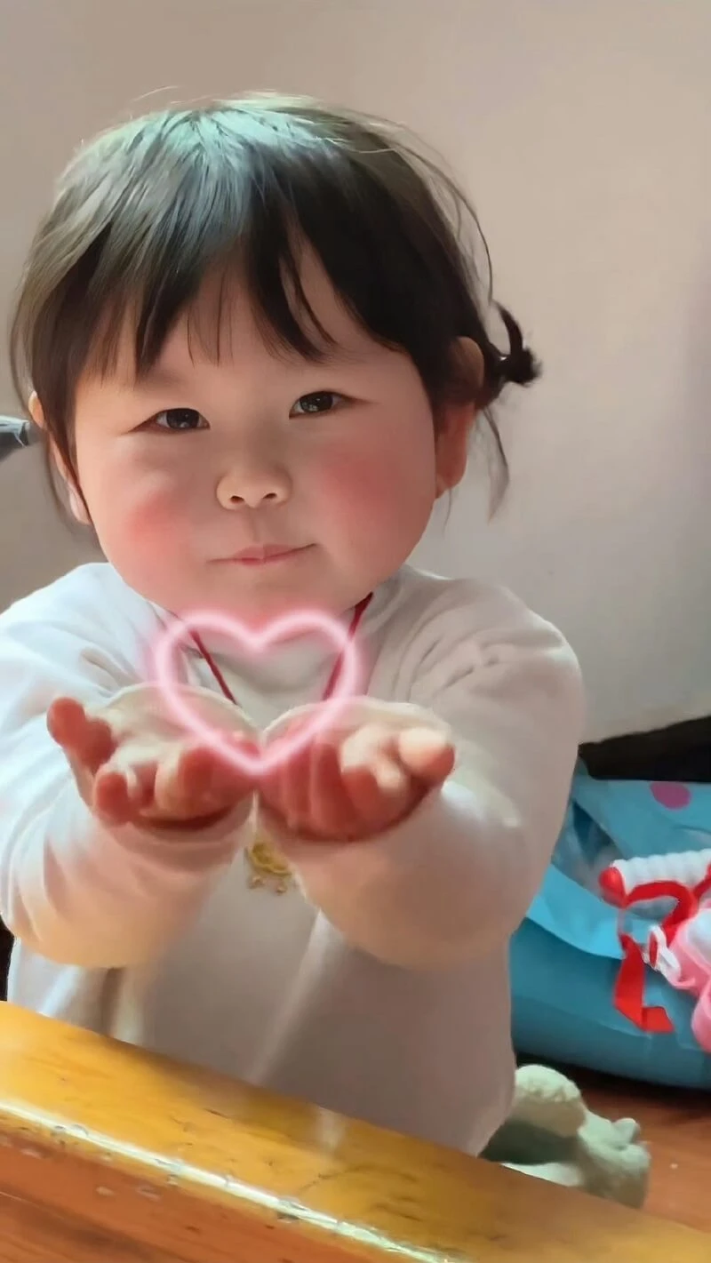 Một cô bé ôm một vật hình trái tim hình nền em bé cute