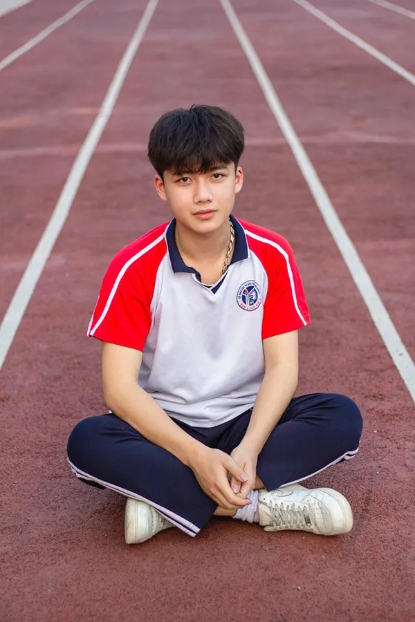 Ảnh trai đẹp đi học có một cậu bé ngồi trên đường đua với đôi chân vượt qua