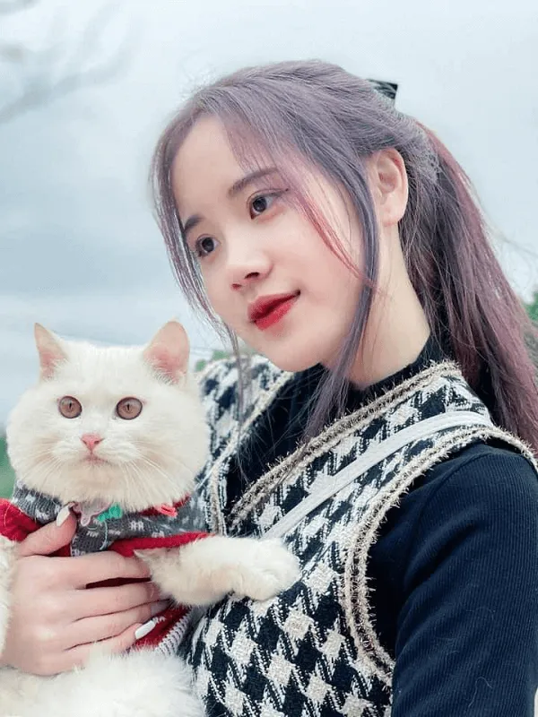Ảnh gái xinh 2k5 che mặt người phụ nữ tóc vàng đang cầm một con mèo trắng đeo cà vạt nơ màu đỏ và đen