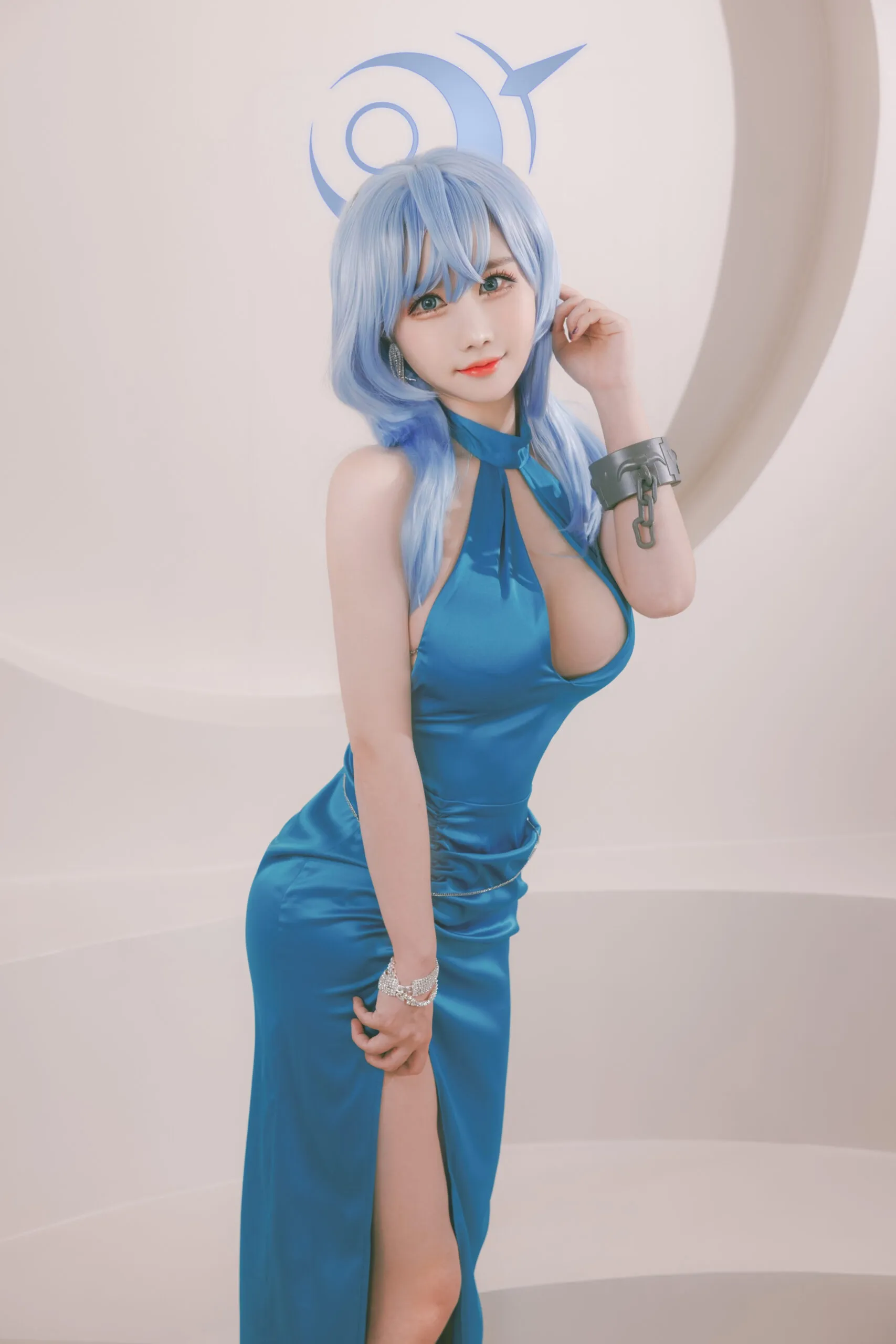 Ảnh amau ako sexy người phụ nữ mặc váy màu xanh tạo dáng trước một bức tường trắng với con chim trên đầu