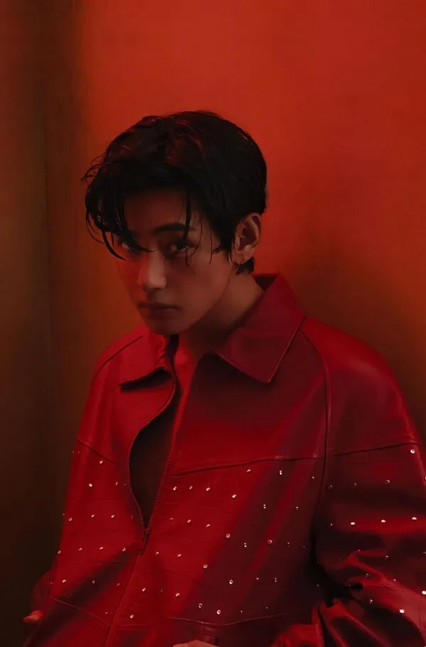 Ảnh bts có một người đàn ông mặc áo khoác đỏ dựa vào bức tường màu