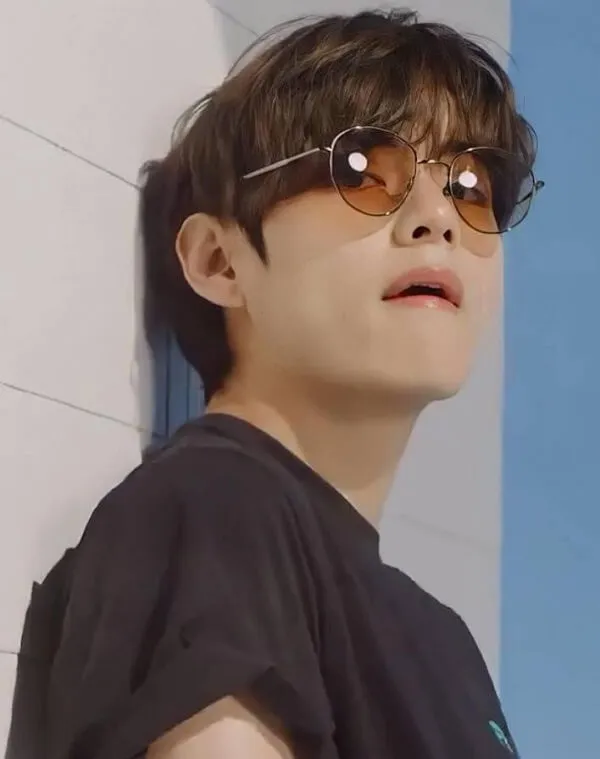 Ảnh bts cute có một thanh niên đeo kính râm dựa vào tường
