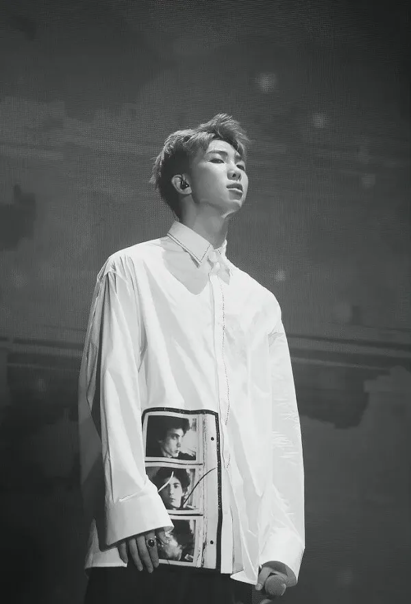 Ảnh rm bts đen trắng của một người đàn ông mặc áo sơ mi cầm ván trượt