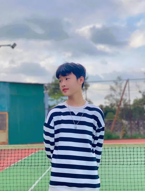 Hình ảnh trai đẹp 12 tuổi có một người đàn ông đứng trên sân tennis cầm cây vợt
