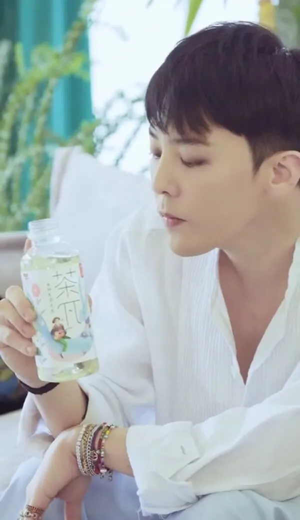 Ảnh của g-dragon có một người đàn ông ngồi trên giường cầm chai sữa