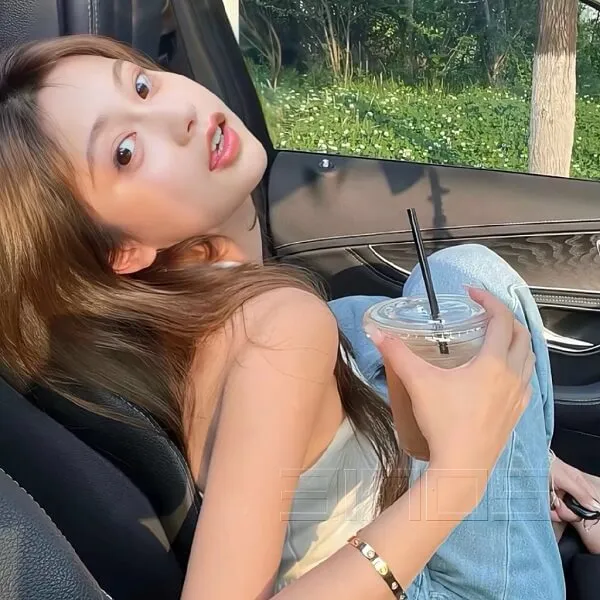 Có một người phụ nữ ngồi trong xe với đồ uống tay