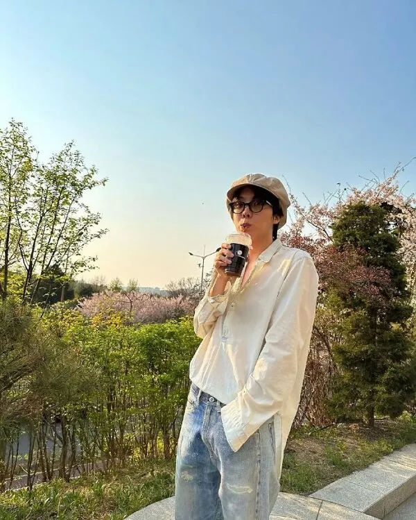 Ảnh j-hope bts có một người phụ nữ đang đứng trên cỏ với điện thoại di động