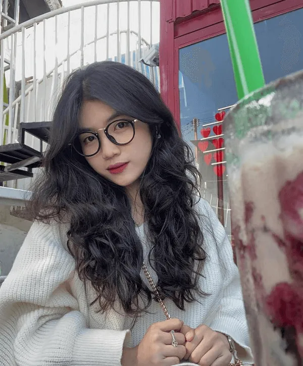 Ảnh gái xinh cute dễ thương người phụ nữ có mái tóc đen dài và kính ngồi trước máy xay chứa đầy kem quả mâm xôi