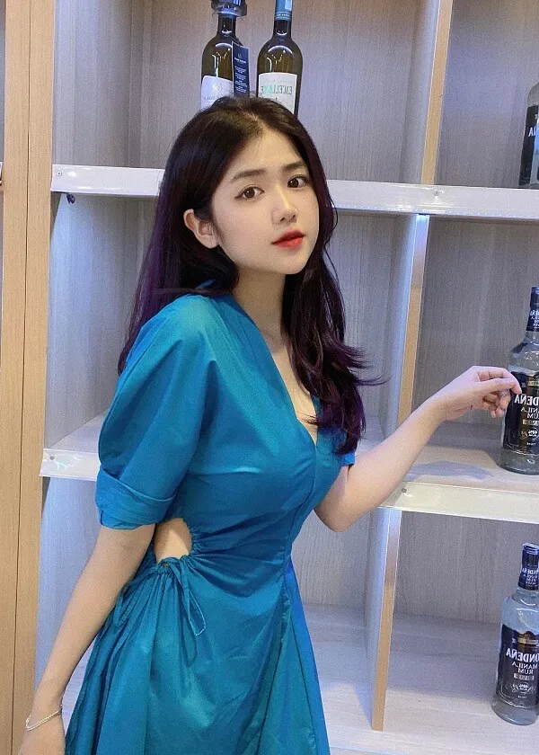 Hình ảnh gái xinh việt nam có một người phụ nữ mặc chiếc váy màu xanh cầm chai rượu
