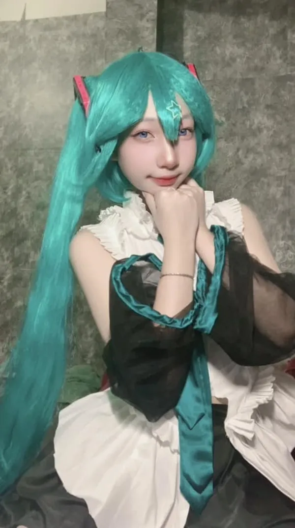 Ảnh hatsune miku cosplay có một người phụ nữ mái tóc dài màu xanh ngồi trên giường