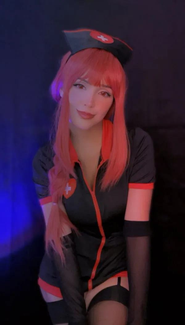 Ảnh sex cosplay makima có một người phụ nữ mái tóc màu hồng mặc trang phục đen và đỏ