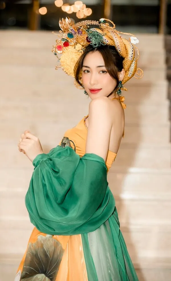 Ảnh hoà minzy sexy có một người phụ nữ mặc chiếc váy màu xanh lá cây và vàng mũ