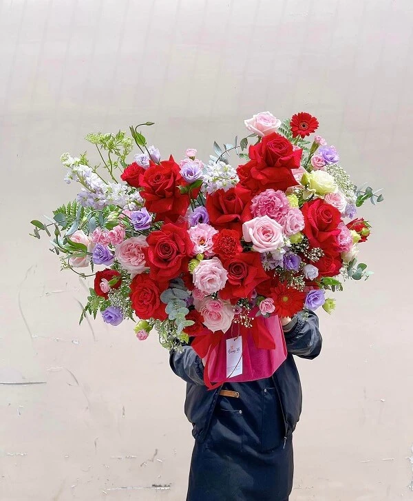 Một người phụ nữ cầm một bó hoa đỏ và hồng ảnh hoa valentine