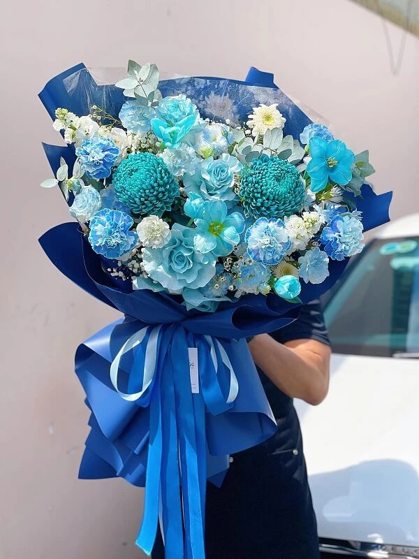 Một người phụ nữ cầm một bó hoa màu xanh ảnh hoa valentine