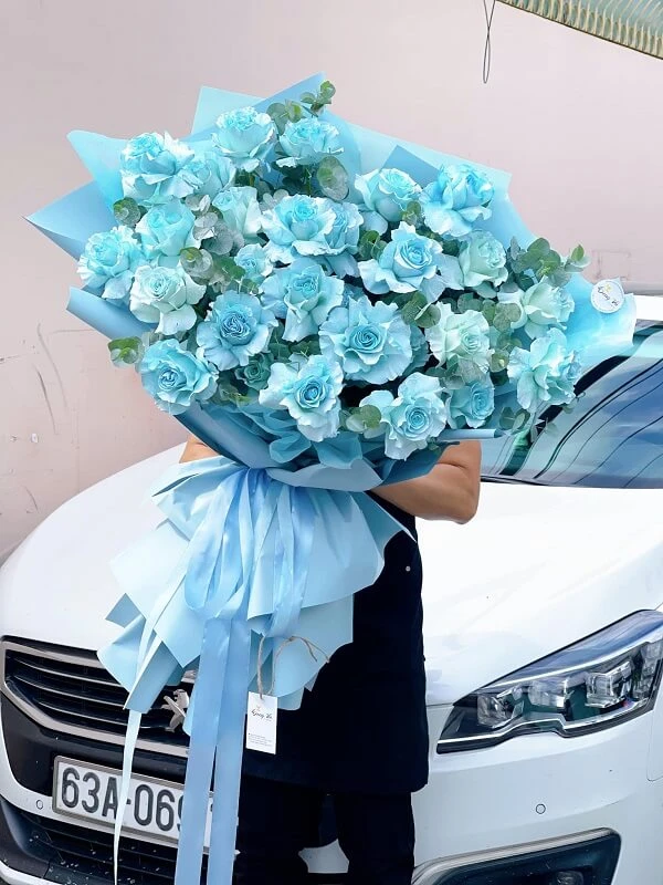 Một người phụ nữ cầm một bó hoa màu xanh ảnh hoa valentine