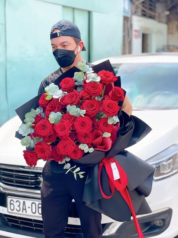 Một người phụ nữ trong mặt nạ cầm một bó hoa hồng đỏ ảnh hoa valentine