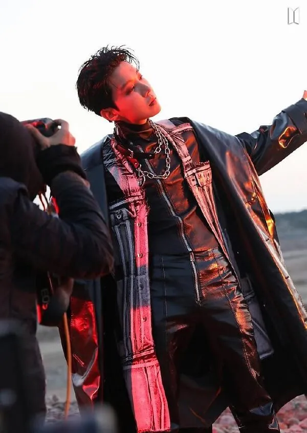 Ảnh j-hope bts có một người đàn ông đang đứng trong bụi bẩn với hai tay ra