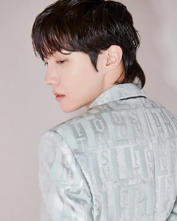 Ảnh j-hope bts người đàn ông châu mặc một bộ đồ và cà vạt đứng trước bức tường trắng