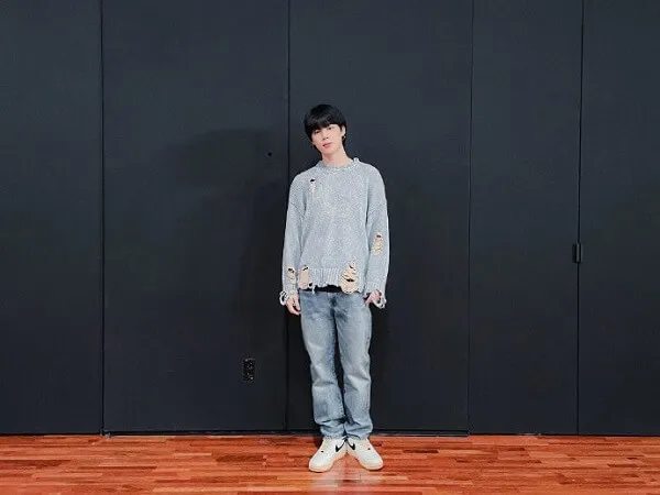 Ảnh jimin đời thường có một chàng trai trẻ đứng trước bức tường đen