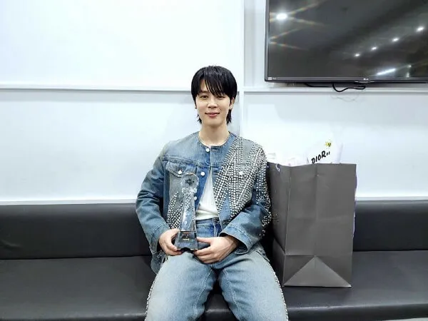 Ảnh jimin cute có một người đàn ông đang ngồi trên chiếc ghế dài với cái túi