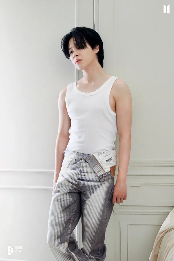 Ảnh jimin có một người đàn ông đứng trước bức tường trắng mặc quần và áo tank