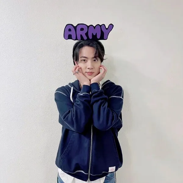Ảnh jin bts có một người đàn ông đứng trước bức tường với từ quân đội