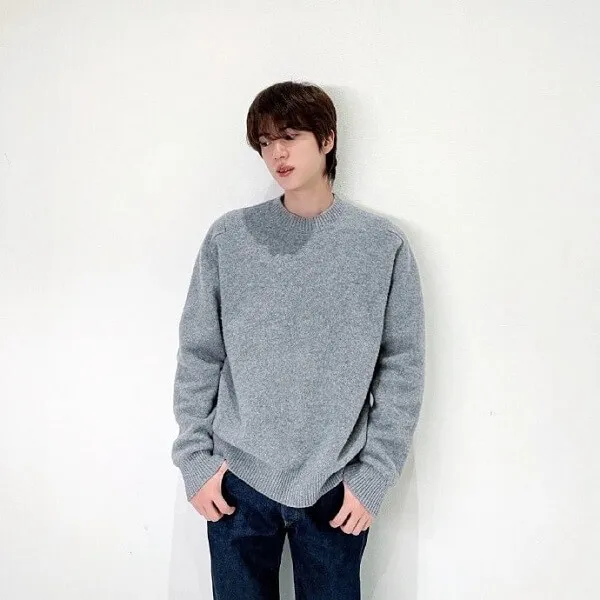 Ảnh jin bts đây là một người đàn ông đứng trên bức tường trắng với hai tay trong túi