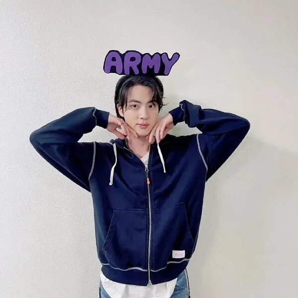 Ảnh jin bts có một người đàn ông đang tạo dáng cho bức với hai tay trên đầu