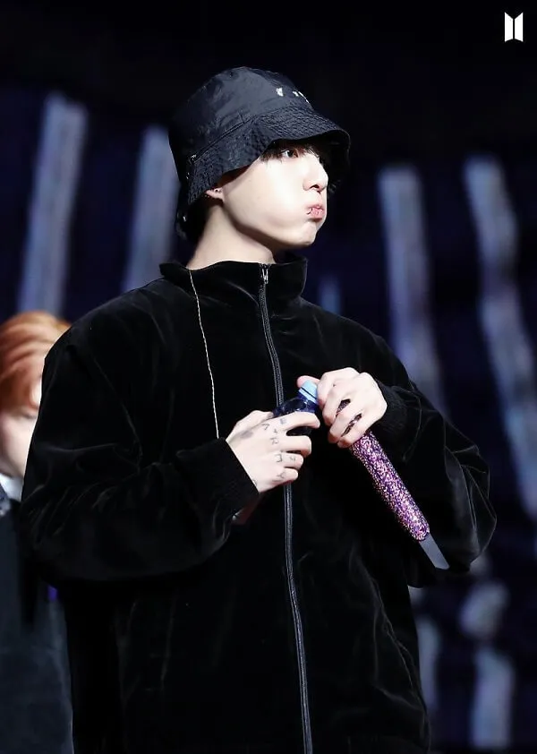 Ảnh jungkook có một chàng trai trẻ mặc áo khoác đen và mũ cầm micro