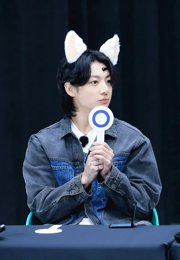 Ảnh jungkook có một người phụ nữ ngồi bàn với micro trong tay