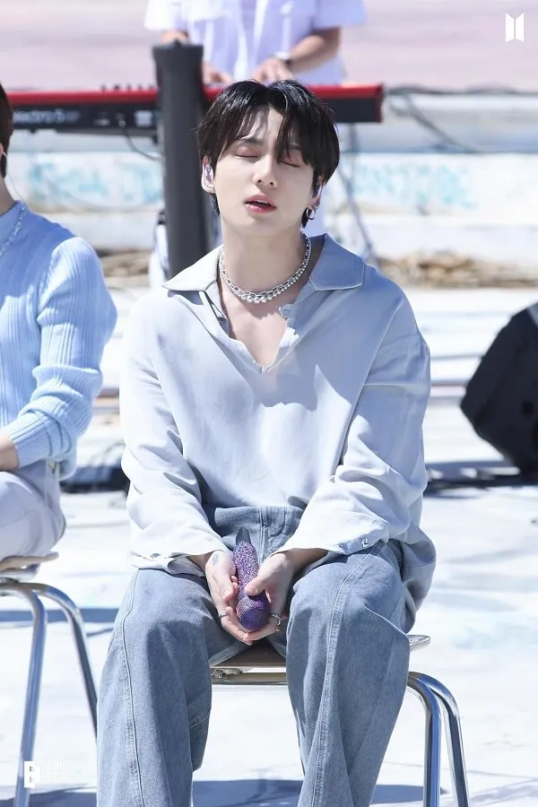 Ảnh jungkook có một người đàn ông đang ngồi trên ghế với điện thoại di động