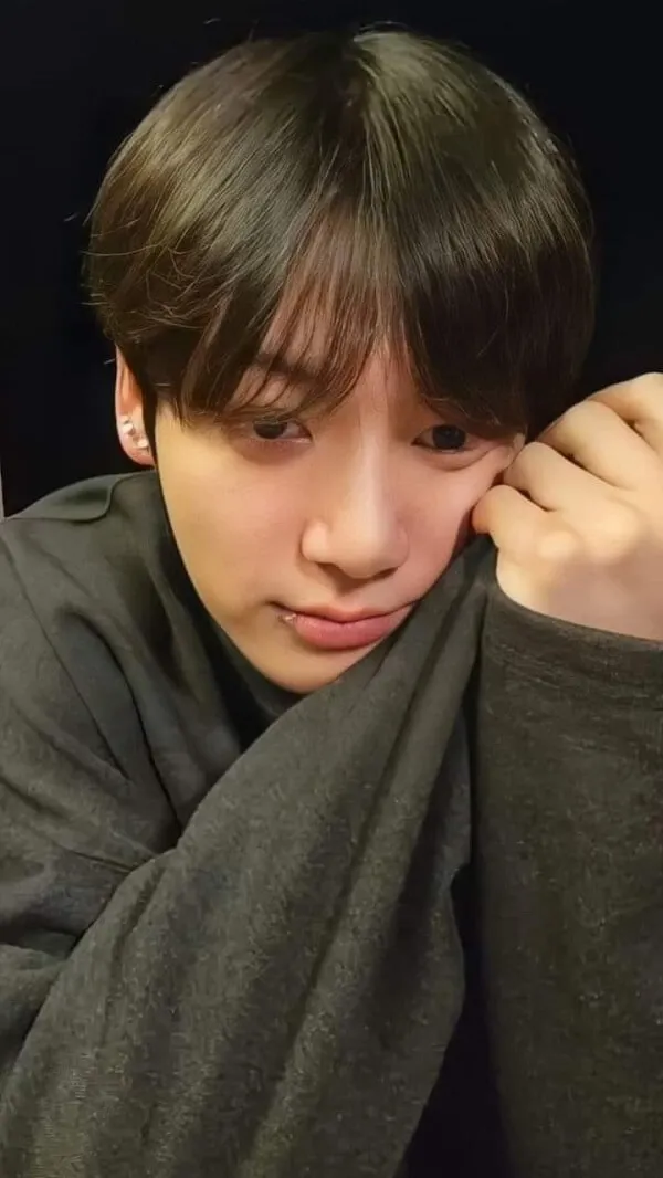 Ảnh jungkook có một người đàn ông ngồi trên bàn với điện thoại di động trong tay
