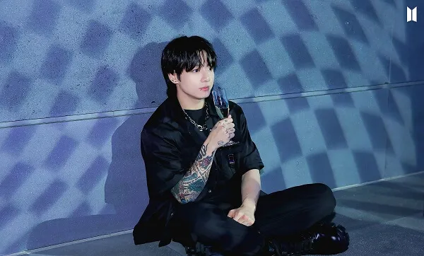 Ảnh jungkook có một người đàn ông ngồi trên mặt đất cầm ly rượu