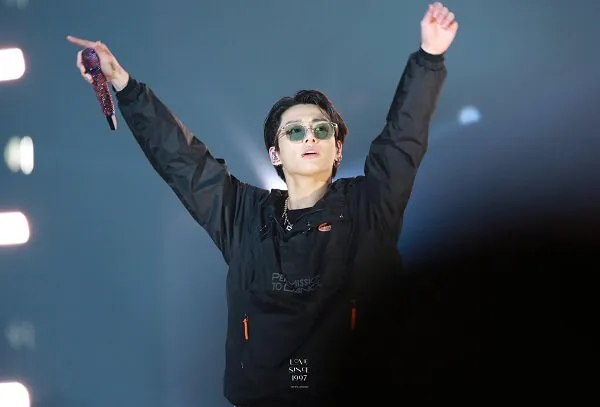 Ảnh jungkook người đàn ông mặc áo khoác đen đang giơ tay lên không trung