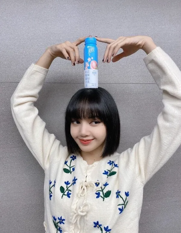Ảnh lisa blackpink có một người phụ nữ đang cầm lon nước trên đầu