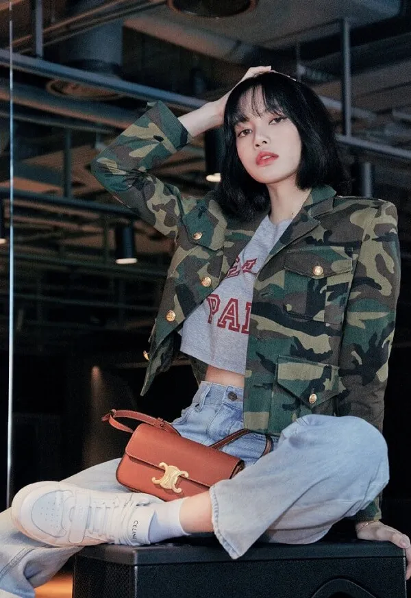 Ảnh lisa dễ thương người phụ nữ châu mặc áo khoác ngụy trang và quần jean ngồi trên chiếc vali
