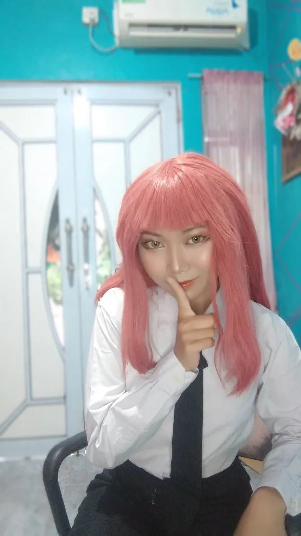Ảnh makima hentai có một người phụ nữ mái tóc hồng và chiếc cà vạt ngồi trên ghế
