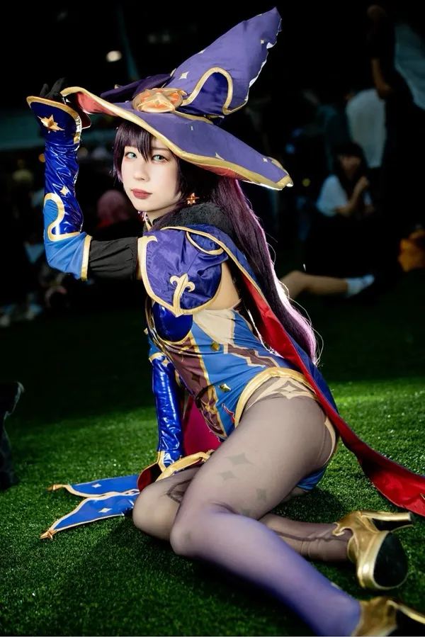 Ảnh mona cosplay có một người phụ nữ đang ngồi trên cỏ với chiếc mũ
