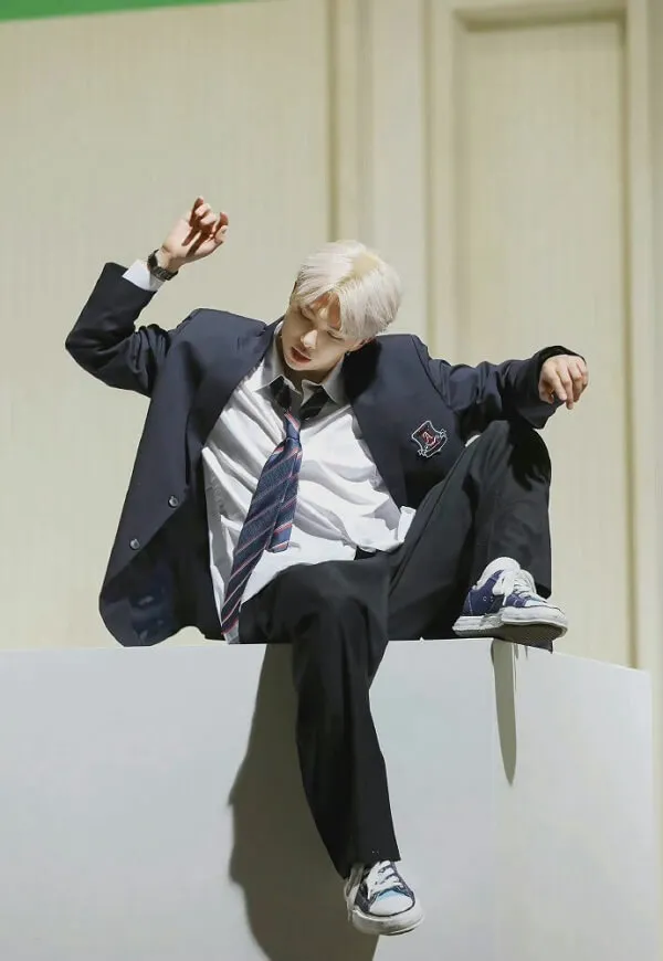 Ảnh rm bts có một người đàn ông trong bộ đồ và cà vạt ngồi trên tường