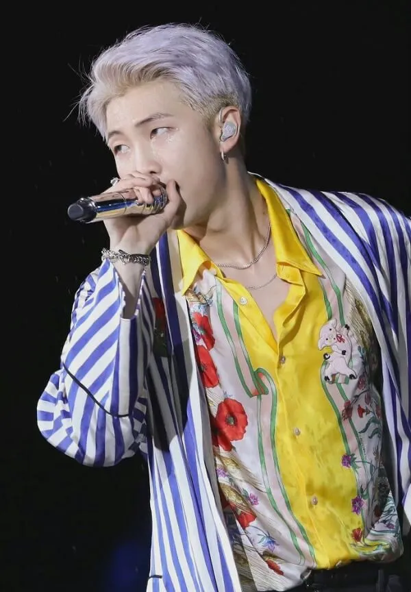 Ảnh rm bts hình một người đàn ông hát vào micro trong khi mặc áo sơ mi sọc
