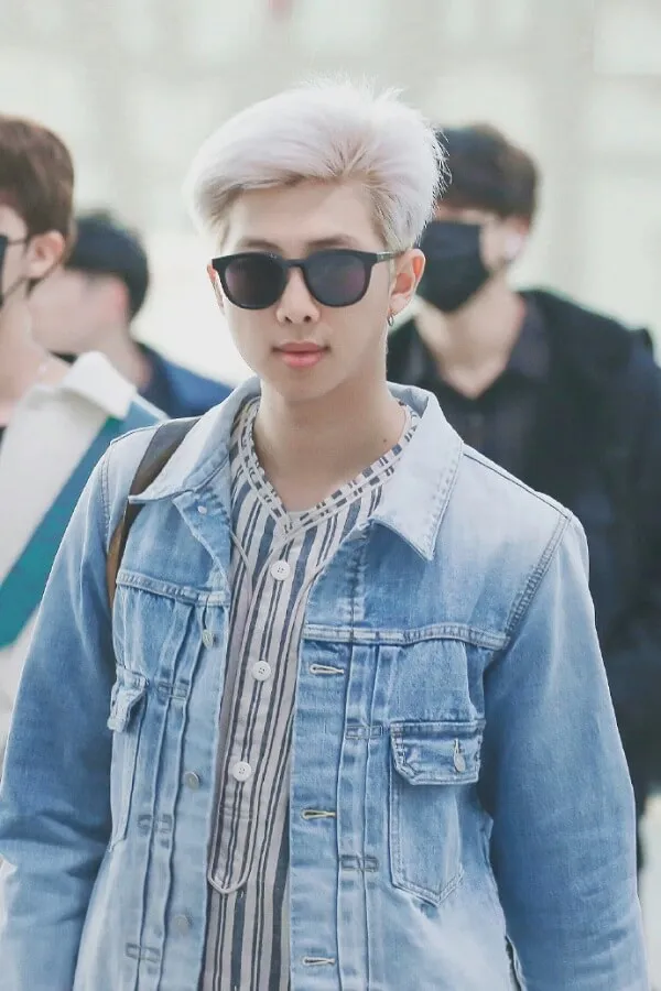 Ảnh của rm bts có một người đàn ông với mái tóc trắng đeo kính râm và áo khoác denim