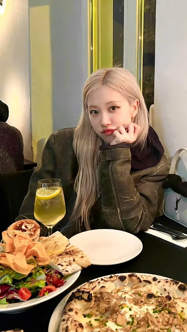 Ảnh rose blackpink đẹp có một người phụ nữ ngồi trên bàn với vài đĩa thức ăn