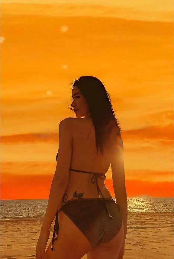 Ảnh sexy hòa minzy bức của một người phụ nữ mặc bikini đứng trên bãi biển vào lúc hoàng hôn