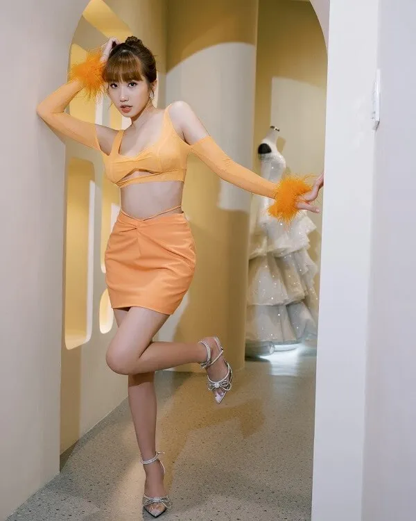 Ảnh sexy lê thị khánh huyền có một người phụ nữ mặc chiếc váy màu cam tạo dáng cho bức tranh