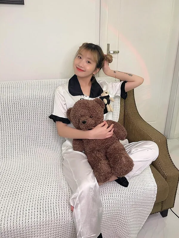 Lê thị khánh huyền có một người phụ nữ đang ngồi trên chiếc ghế dài với con gấu bông